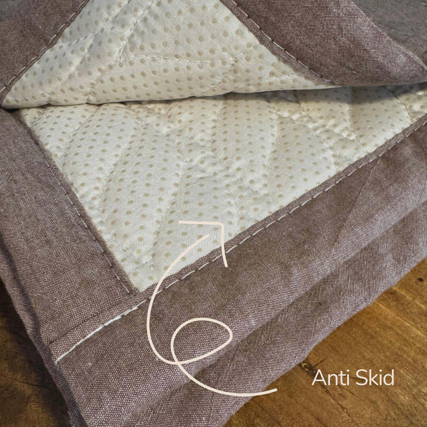 Textured fabric surface with stitching detail on a wooden floor, featuring 'Anti Skid' text.