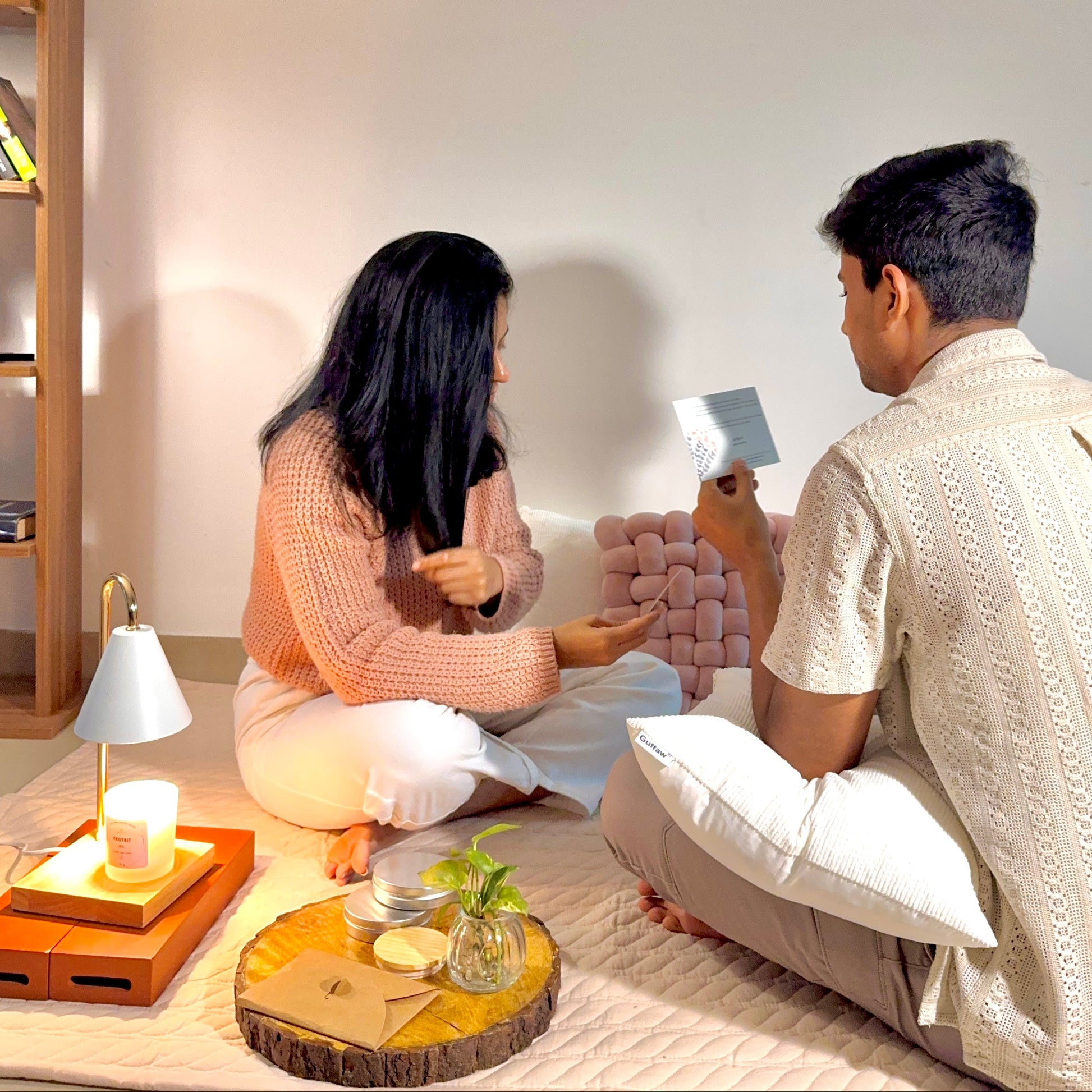 Two people sitting on the floor in a room with a small table and decor items.