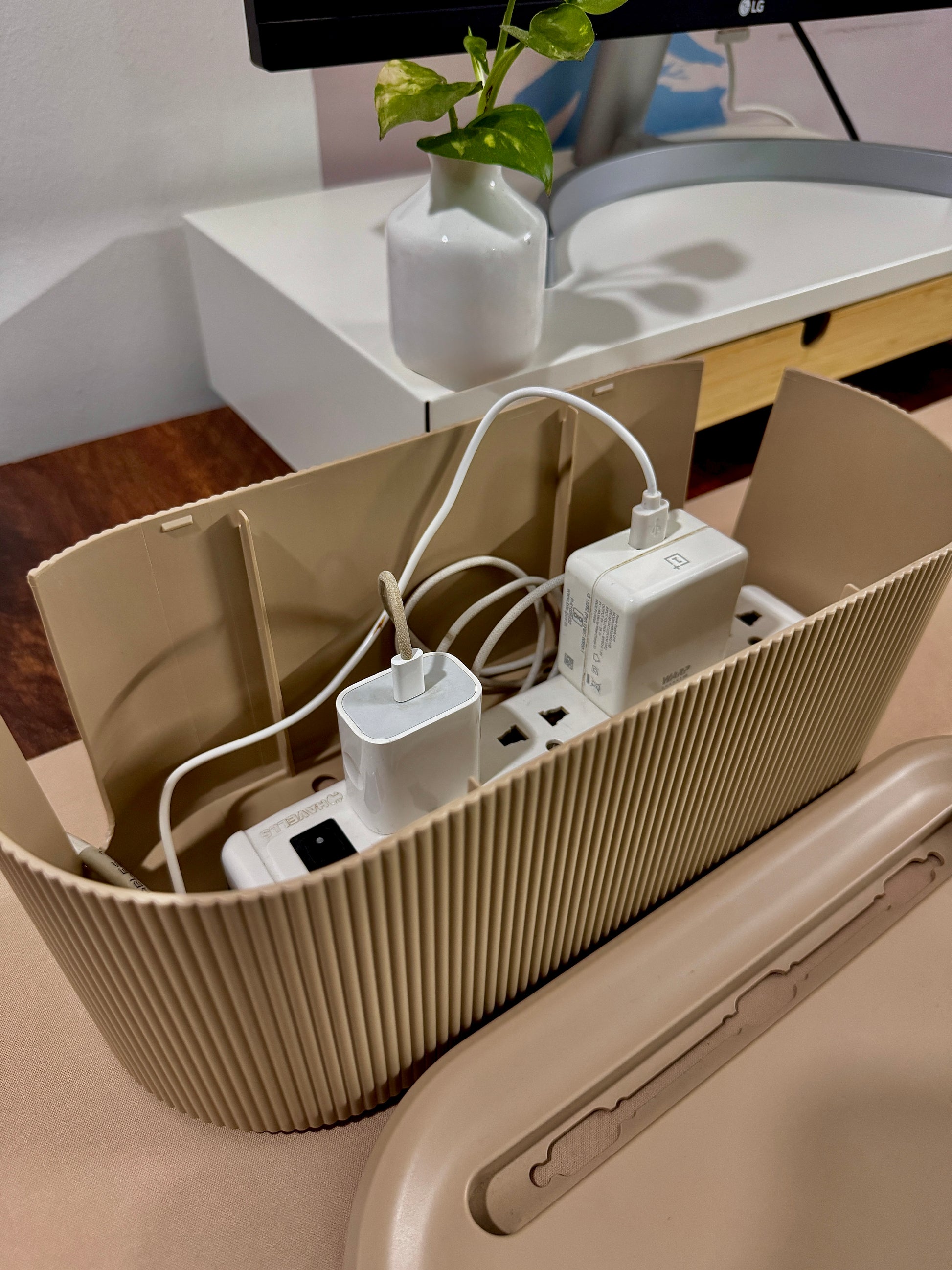 Beige Cable Management box  with multiple outlets and plugs on a desk.